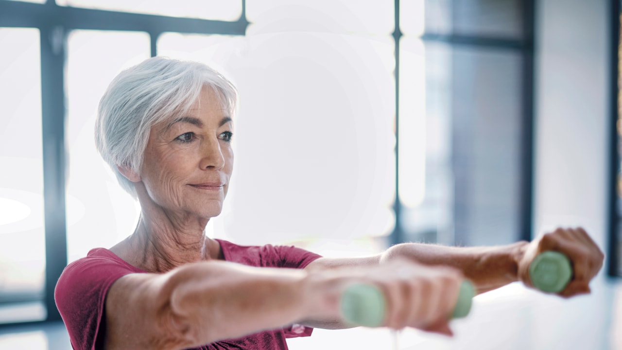 Woman exercising by lifting hand weights in the gym.