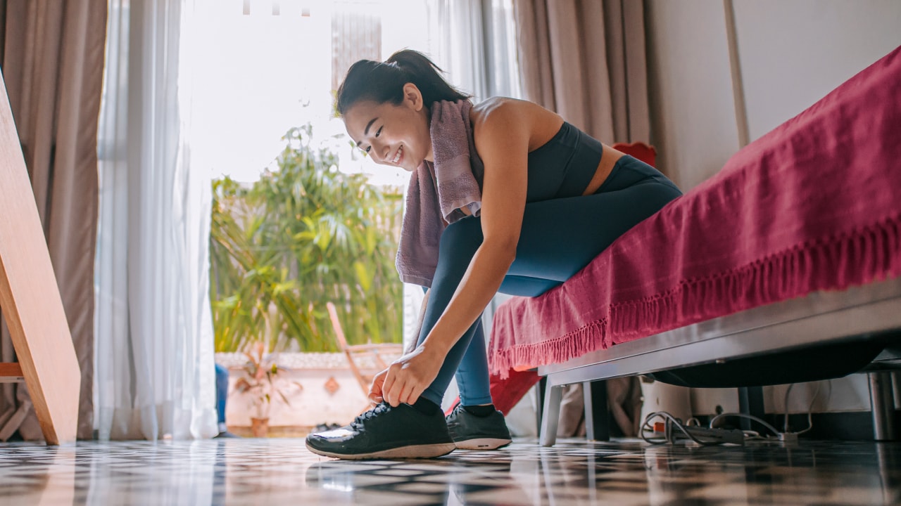 Woman putting her running trainers on while dressed in active gear.