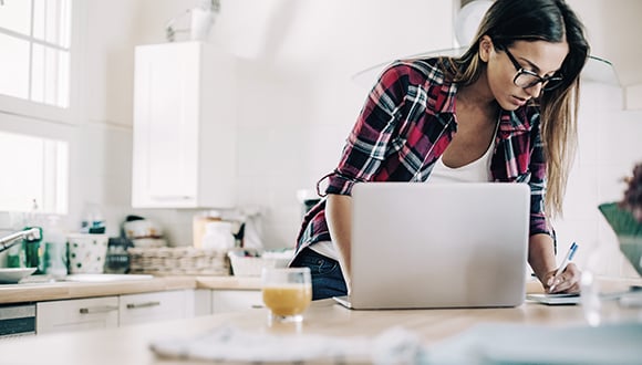 Woman with flexible working arrangements using laptop in kitchen