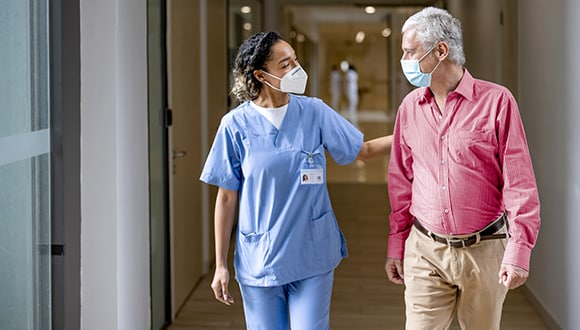 man walking with nurse in hospital