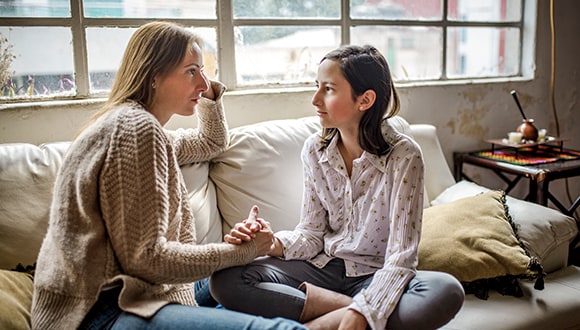 mother and daughter talking on sofa