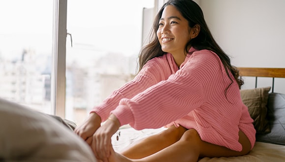 Lady sitting on a her bed after a good night sleep