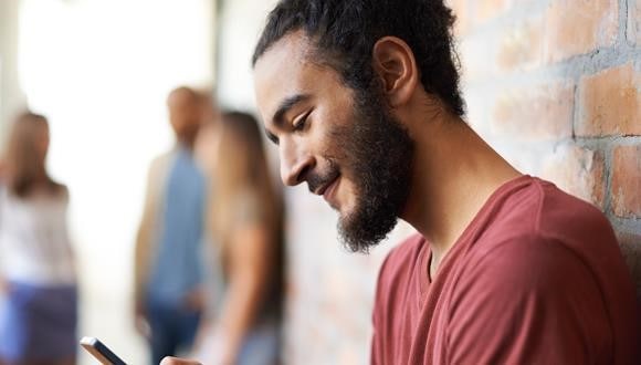 A man smiling and looking at her phone while navigating online dating