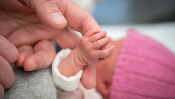 Father holding the hand of his baby following its premature birth