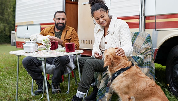 Couple outside their holiday caravan, patting their dog